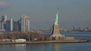 AX0065_0078E - 5K aerial stock footage orbit the torch side of the Statue of Liberty, New York, reveal Lower Manhattan skyline in the background, winter