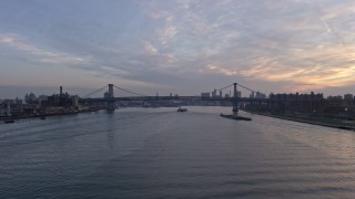 AX0065_0170 - 5K aerial stock footage follow the East River to approach barges near the Williamsburg Bridge, New York City, winter, sunset