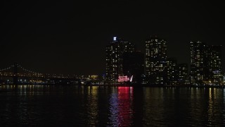 AX0065_0307E - 5K aerial stock footage low approach to the Pepsi Sign and waterfront apartment buildings in Queens, New York City, winter, night