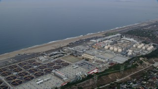 AX0156_186E - 7.6K aerial stock footage flying over coastal community towards Dockweiler beach and water treatment plant, sunrise, El Segundo, California