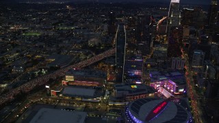 AX0158_061 - 7.6K aerial stock footage flying by Staples Center, skyscrapers, and heavy 110 traffic at twilight, Downtown Los Angeles, California