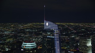 AX0158_115E - 7.6K aerial stock footage orbiting the top of Wilshire Grand Center and reveal US Bank Tower at night, Downtown Los Angeles, California