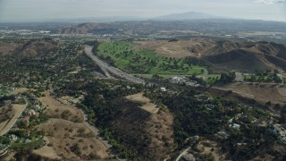 AX0159_130E - 7.6K aerial stock footage following the I-10 freeway between homes and Forest Lawn Covina Hills Cemetery, Covina, California