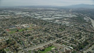 7.6K aerial stock footage flying over homes and Don Antonio High School, approach warehouses, Chino, California Aerial Stock Footage | AX0159_136E