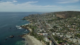 AX0159_210 - 7.6K aerial stock footage flying over beach toward highway surrounded by houses; Laguna Beach, California