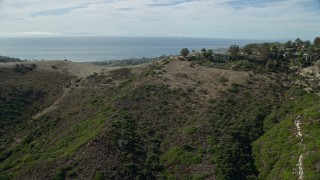 7.6K aerial stock footage flying over hill to reveal coastal community below, Laguna Beach, California Aerial Stock Footage | AX0159_215E