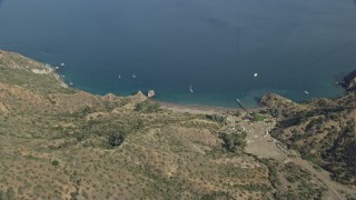 AX0159_269 - 7.6K aerial stock footage of a reverse view of a campground, beach, and sailboats on the coast of Santa Catalina Island, California