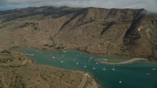 AX0160_012E - 7.6K aerial stock footage of fly over hills toward sailboats in Catalina Harbor in Two Harbors, Santa Catalina Island, California