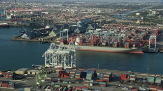 AX0161_009 - 7.6K aerial stock footage of cranes loading containers onto a ship at the Port of Long Beach, California