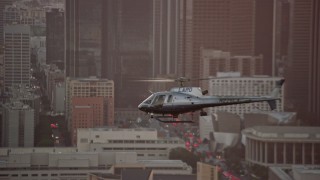 AX0162_095E - 7.6K aerial stock footage tracking an LAPD helicopter flying by Downtown Los Angeles, California at twilight