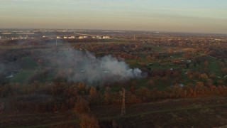 4K aerial stock footage of a fire in the trees at a golf course at sunset in Lockport, Illinois Aerial Stock Footage | AX0163_0004