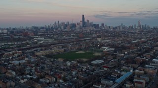 4K aerial stock footage of tilting from an urban West Side neighborhood to reveal the Chicago skyline at sunset, Illinois Aerial Stock Footage | AX0163_0023