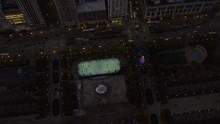 AX0163_0051 - 4K aerial stock footage a bird's eye of the ice skating rink by the Cloud Gate in Grant Park at twilight, Downtown Chicago, Illinois