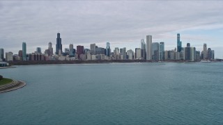 4K aerial stock footage of flying past Adler Planetarium to approach Downtown Chicago skyline, Illinois Aerial Stock Footage | AX0165_0063