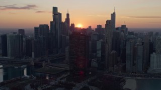 4K aerial stock footage of flying by waterfront skyscrapers with setting sun in the distance, Downtown Chicago, Illinois Aerial Stock Footage | AX0170_0023