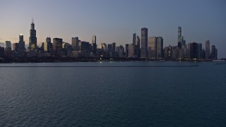 4K aerial stock footage fly near Adler Planetarium toward the Downtown Chicago skyline at twilight, Illinois Aerial Stock Footage | AX0170_0052