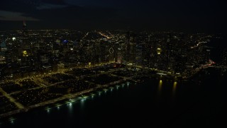 4K aerial stock footage of approaching Grant Park and downtown skyscrapers, some with holiday lights at night, Downtown Chicago, Illinois Aerial Stock Footage | AX0170_0079