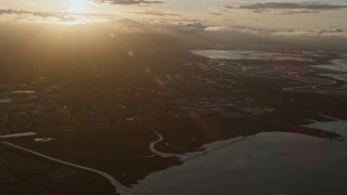 AX0174_0050 - 6K aerial stock footage of approaching a suburban neighborhood and warehouses at sunset, East Palo Alto, California