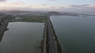 6K aerial stock footage tilt from Bayshore Fwy to reveal the distant San Francisco skyline at sunset, California Aerial Stock Footage | AX0174_0071