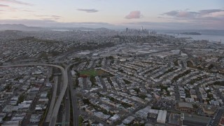 AX0174_0075 - 6K aerial stock footage tilt from 101 freeway to reveal the distant San Francisco skyline at sunset, California