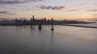 6K aerial stock footage of flying beside the Bay Bridge toward the Downtown San Francisco skyline at sunset, California Aerial Stock Footage | AX0174_0090