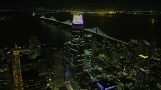 AX0174_0197 - 6K aerial stock footage of flying past downtown skyscrapers toward Bay Bridge at night, San Francisco, California