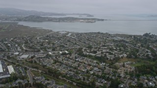 AX0175_0041 - 6K aerial stock footage fly over Corte Madera neighborhoods, San Quentin in the distance, on a foggy day, California