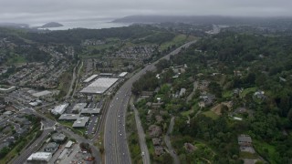 AX0175_0058 - 6K aerial stock footage tilt from light traffic on 101 freeway through Corte Madera on a foggy day, California