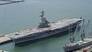 AX0175_0100 - 6K aerial stock footage of an aircraft carrier docked in Alameda, California