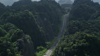 AX101_085E - 4.8K aerial stock footage Flying above highway cutting through lush green mountains, Karst Forest, Puerto Rico