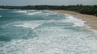 4.8K aerial stock footage flying low over clear blue waters along a beach, Arecibo, Puerto Rico Aerial Stock Footage | AX101_150E