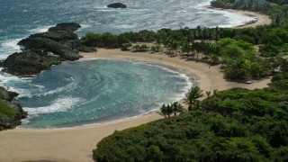 AX101_189E - 4.8K aerial stock footage of following rocky coast to coastal tide pool bordering clear blue waters, Manati, Puerto Rico