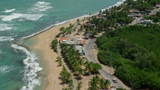 AX102_015E - 4.8K aerial stock footage of coastal shops, highway and beach beside crystal turquoise waters, Loiza, Puerto Rico