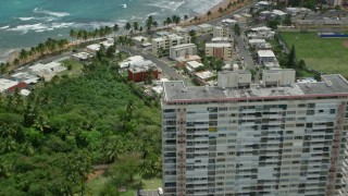 AX102_050E - 4.8K aerial stock footage fly over condos and beachfront property, tilt to reveal jungle by the beach, Luquillo, Puerto Rico