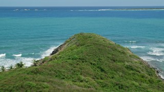 AX102_071E - 4.8K aerial stock footage Flying over a cliff to crystal clear blue water, Fajardo, Puerto Rico