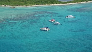 AX102_073E - 4.8K aerial stock footage of catamarans in tropical blue waters with reefs near an island, Rada Fajardo, Puerto Rico