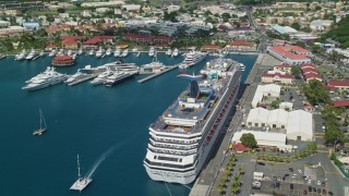 AX102_209E - 4.8K aerial stock footage of a cruise ship and yachts in sapphire waters along a coastal town, Charlotte Amalie, St. Thomas