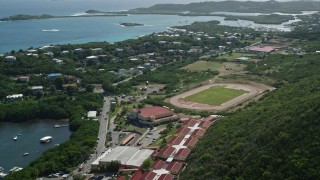 4.8K aerial stock footage of a High school track field near blue coastal waters, East End, St Thomas Aerial Stock Footage | AX102_244