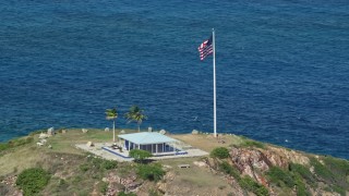 4.8K aerial stock footage Orbiting an oceanfront guesthouse and American flag, Little St James Island, St Thomas Aerial Stock Footage | AX102_251