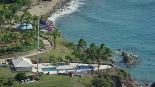 AX102_254 - 4.8K aerial stock footage of an Oceanfront pool and American flag along Caribbean blue waters, Little St James Island, St Thomas 