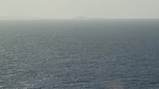 4.8K aerial stock footage flying over a glistening ocean with an island in the distance, Puerto Rico Aerial Stock Footage | AX103_103E