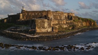 4.8K aerial stock footage of Fort San Felipe del Morro along calm ocean waters, Old San Juan, sunset Aerial Stock Footage | AX104_030