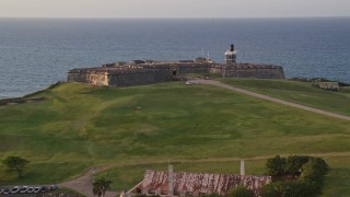 AX104_042 - 4.8K aerial stock footage of Fort San Felipe del Morro overlooking the ocean, Old San Juan sunset