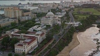 AX104_077 - 4.8K aerial stock footage of San Juan Capitol Building along the coast, Puerto Rico, sunset