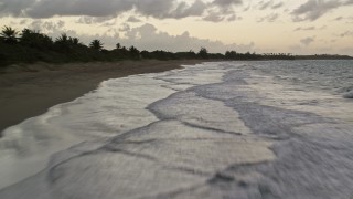 AX104_102E - 4.8K aerial stock footage of blue waters along Caribbean beach with palm trees, Dorado, Puerto Rico, twilight