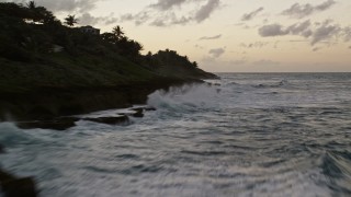 AX104_106E - 4.8K aerial stock footage flying over the ocean toward oceanfront homes, the following the coast, Dorado, Puerto Rico, twilight