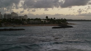 AX104_109 - 4.8K aerial stock footage of a Caribbean hotel on the coast along ocean waters, Dorado, Puerto Rico, twilight