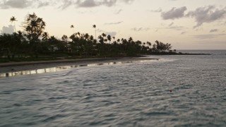 AX104_112E - 4.8K aerial stock footage flying over the ocean past homes and a Caribbean beach, Dorado, Puerto Rico, twilight