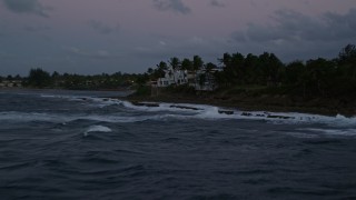 AX104_129E - 4.8K aerial stock footage fly low over ocean along coast and oceanfront homes, Dorado, Puerto Rico, twilight