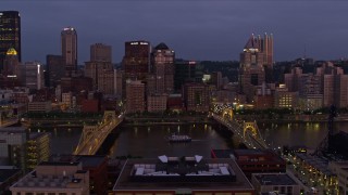 AX108_118E - 4K aerial stock footage flying by bridges and Downtown Pittsburgh skyscrapers, Pennsylvania, twilight